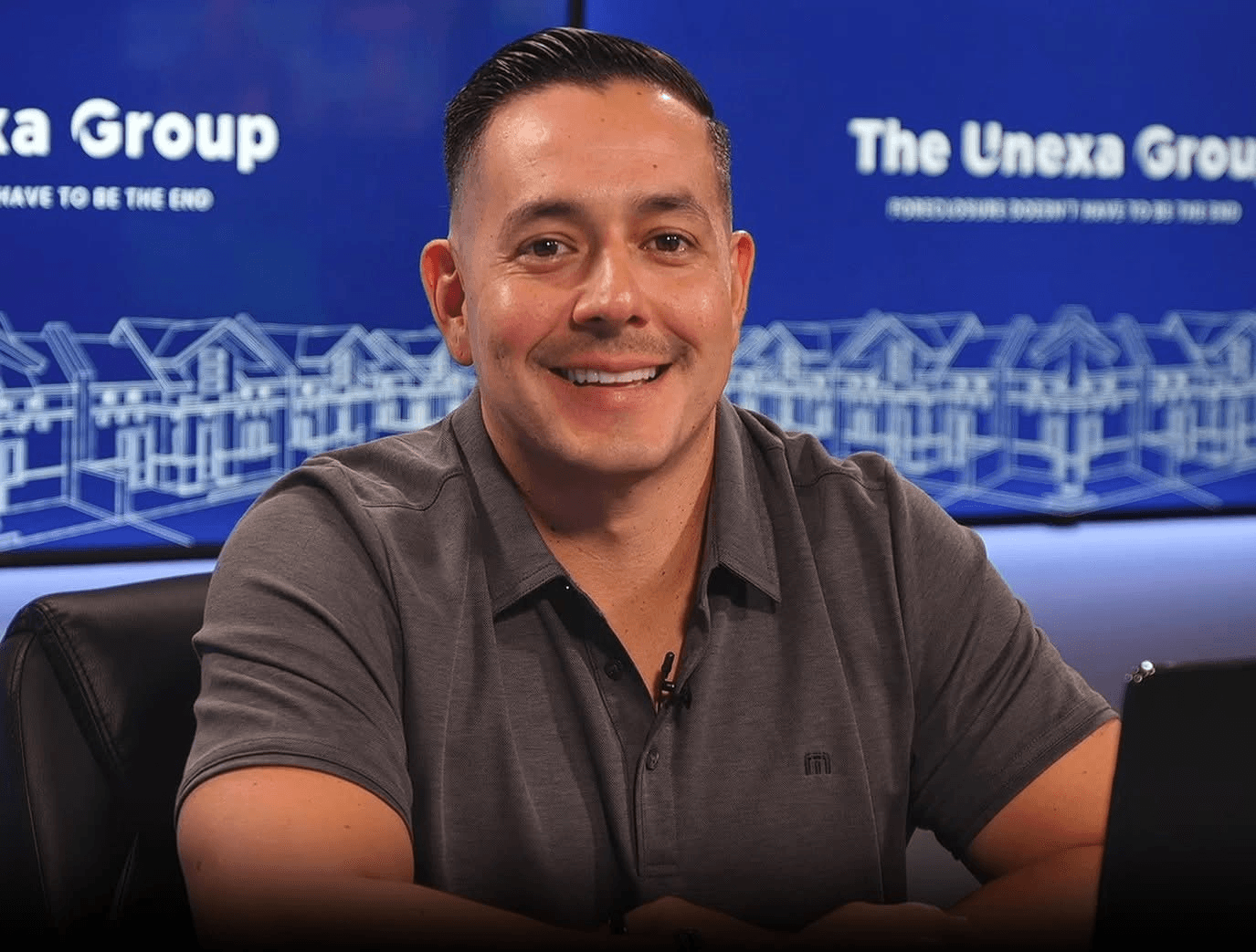 Alfred Taren sitting in front of The Unexa Group backdrop